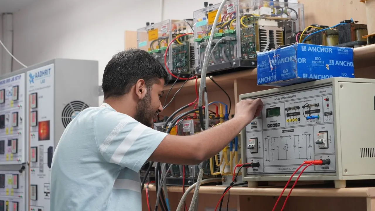 Engineering student operating a power electronics trainer in a college lab