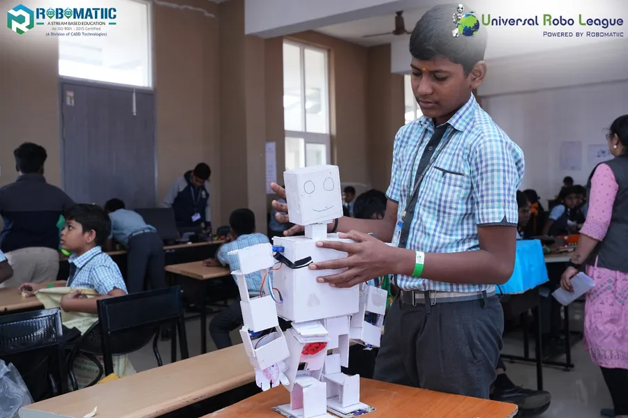 A student assembling a humanoid robot model at a Robomatiic event